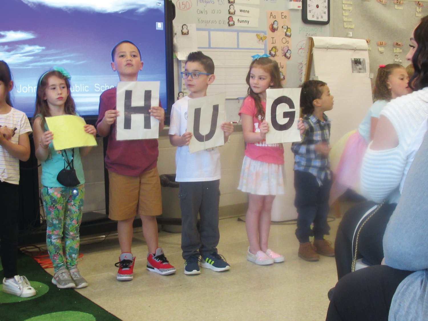 PERFECT PLACARDS: As Isabella Pacitto holds a sign she made showing the title of the class theme song “HUGS,” students Matteo Pari, Anthony Pezzillo and Aria Pratt made individual letters for last week’s classic kindness celebration.